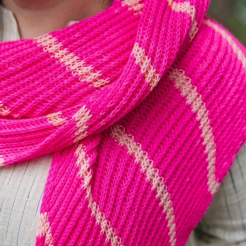 Close-up of a bright pink knitted scarf with gold accents