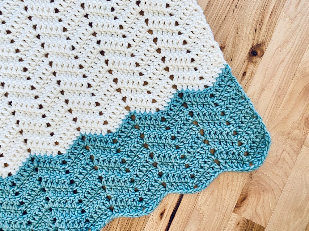 a crocheted blanket in blue and white