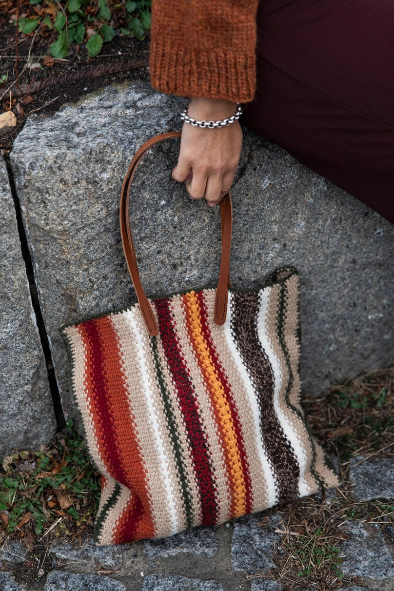 a crocheted bag with earth tone stripes
