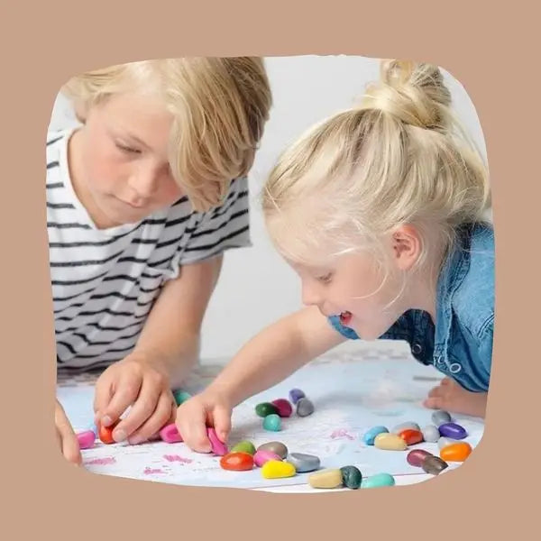 Two children playing with colorful crayons on a white surface.