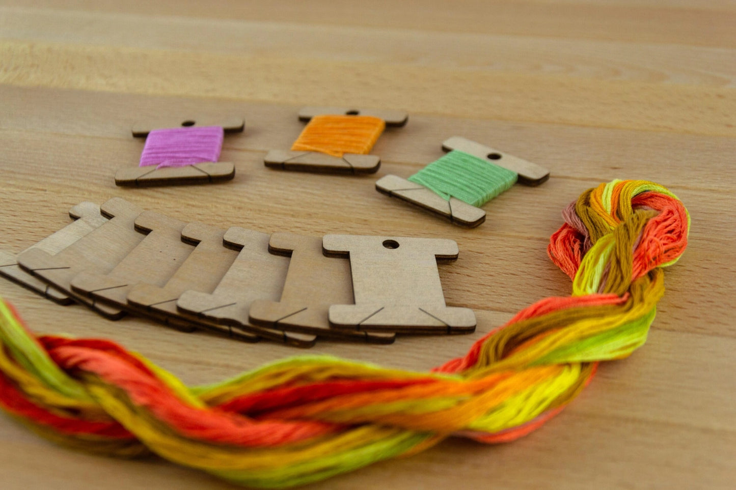 10 wooden thread bobbins and thread on a wooden surface