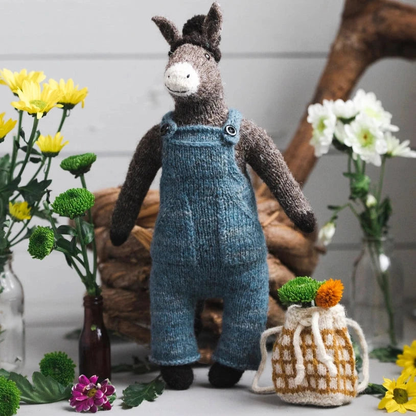 a knitted donkey wearing blue overalls