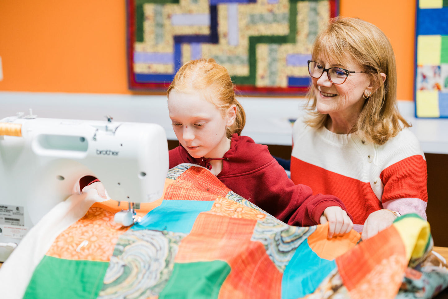 an older woman seated with a child at a sewing machine