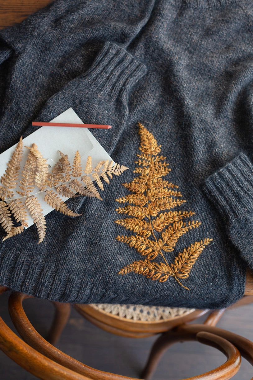 a gray sweater embroidered with a yellow fern