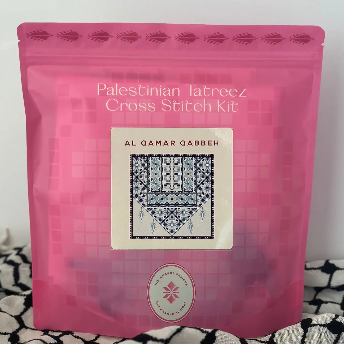 a pink pouch with a cross stitch kit in blue thread