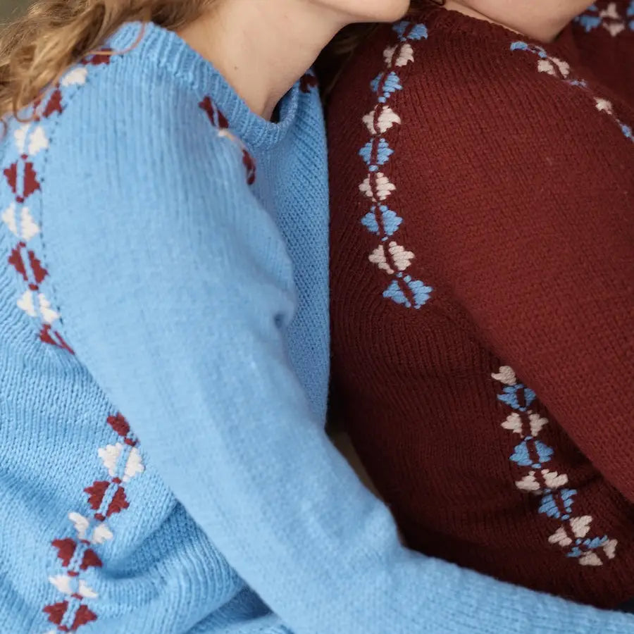 Close-up of two sweaters with intricate patterns on the sleeves.