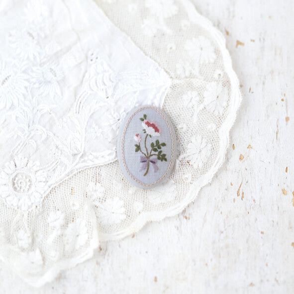 a blue embroidered broach on a piece of lace