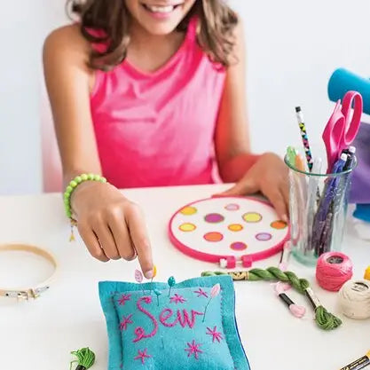a blue felt pincushion embroidered with he word sew