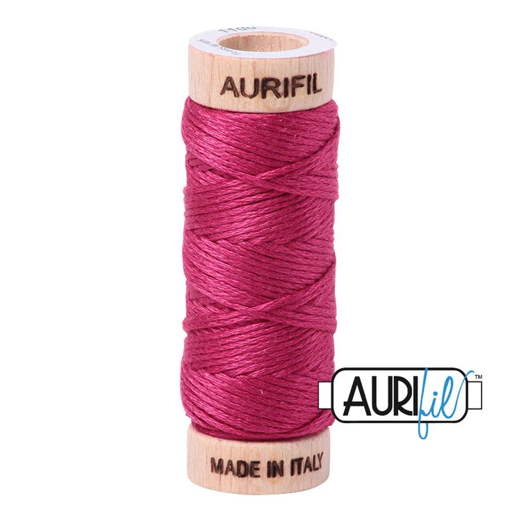 A spool of Aurifil 6-strand embroidery floss in hot pink color, wound around a wooden spool with the brand name visible.