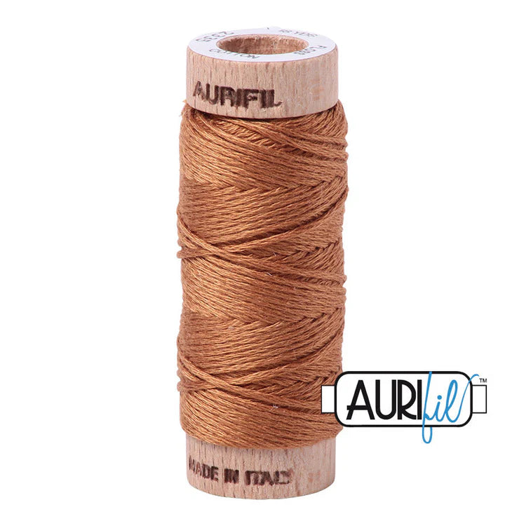 A spool of Aurifil 6-strand embroidery floss in light brown color, wound around a wooden spool with the brand name visible.