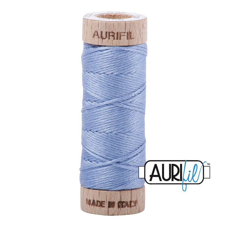 A spool of Aurifil 6-strand embroidery floss in light blue color, wound around a wooden spool with the brand name visible.