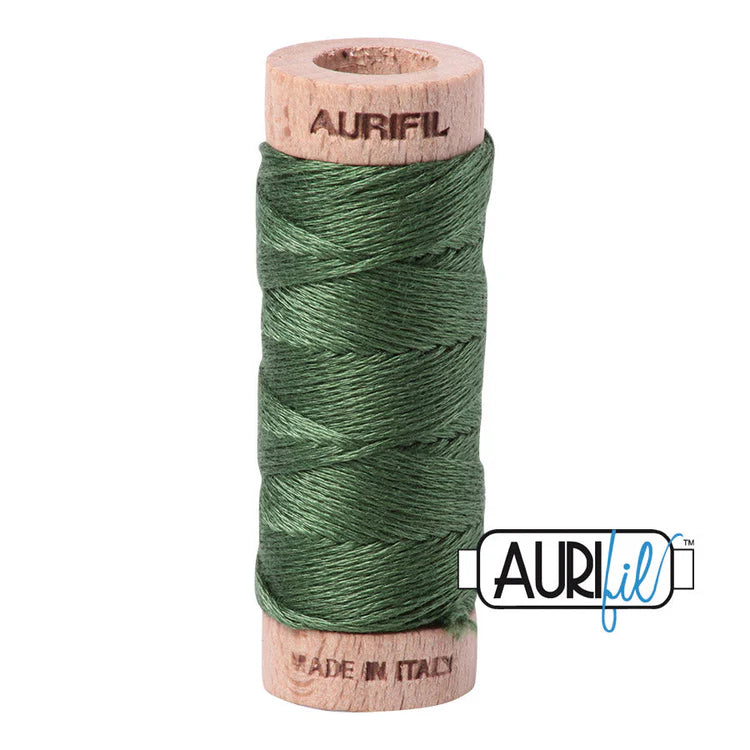 A spool of Aurifil 6-strand embroidery floss in grass green color, wound around a wooden spool with the brand name visible.