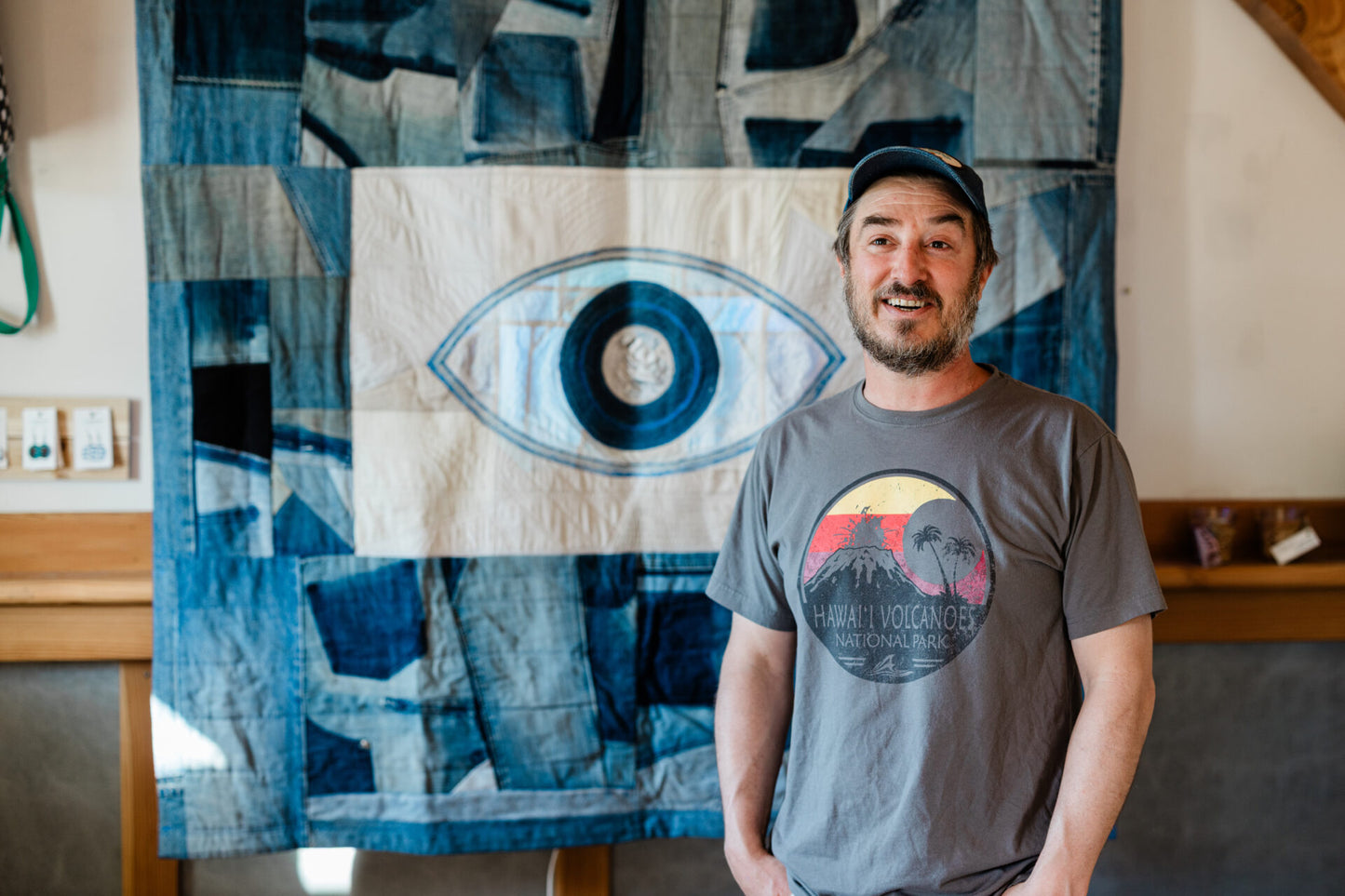 Man standing in front of a large abstract art piece with an eye design.