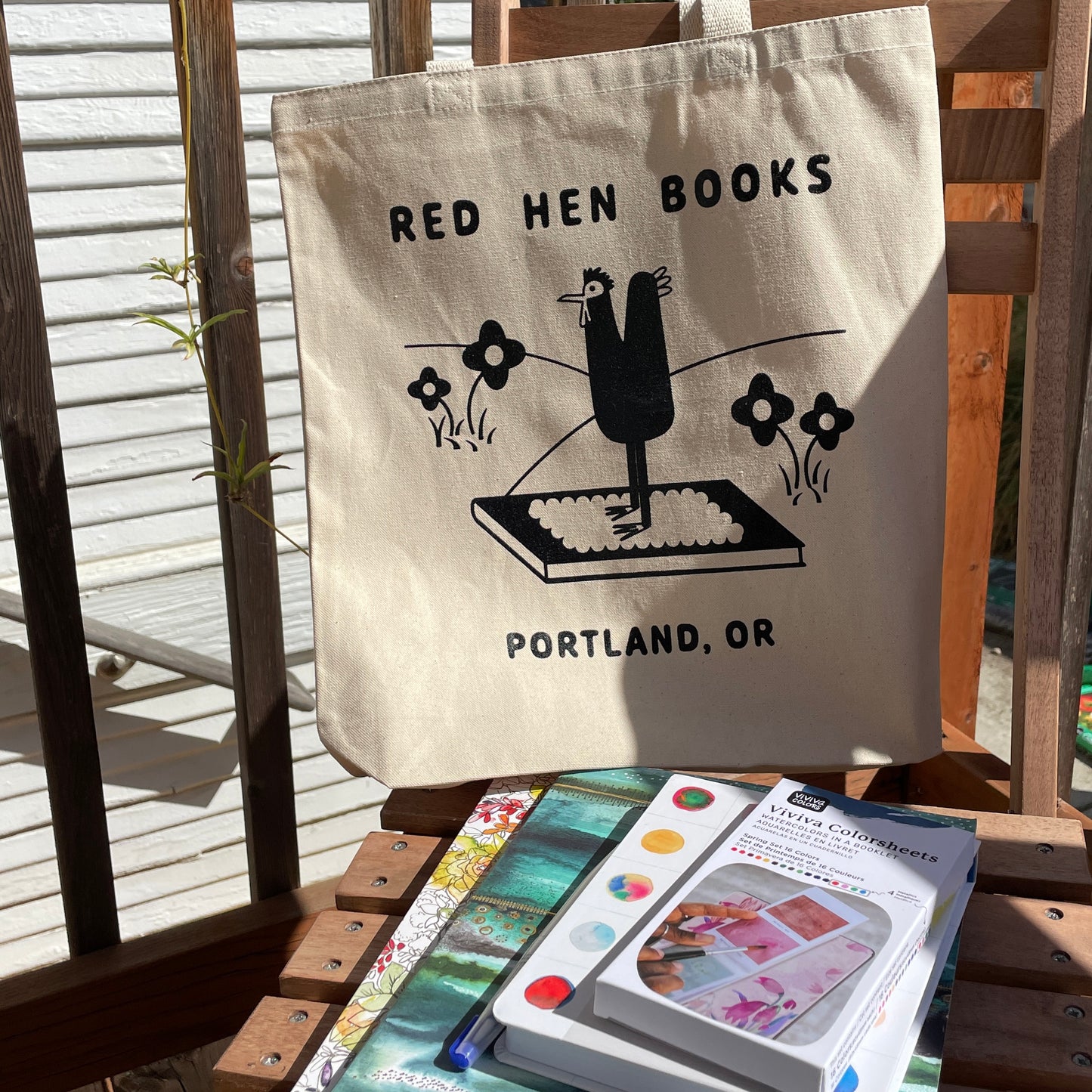 A natural tote bag with a stack of craft books and supplies