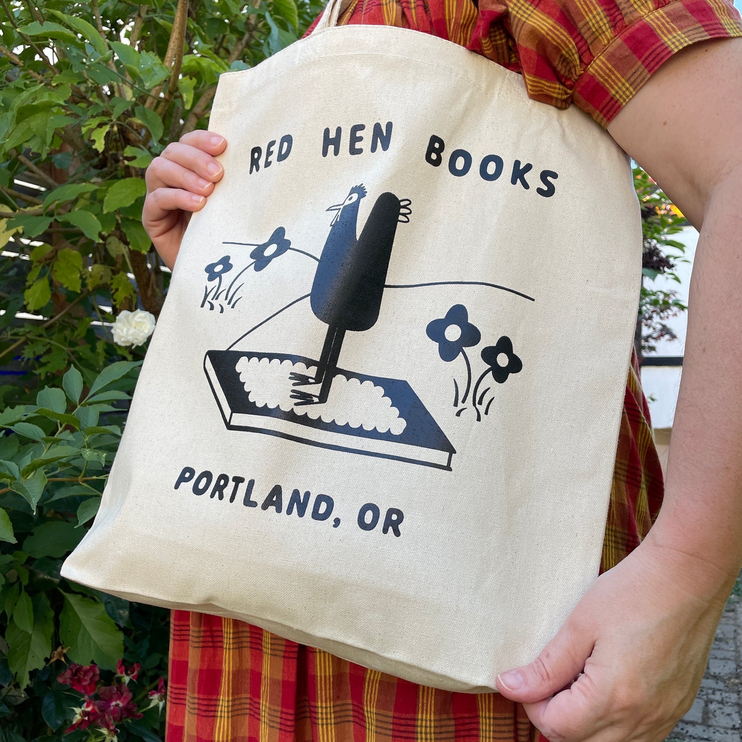 a natural tote bag with a red hen graphic