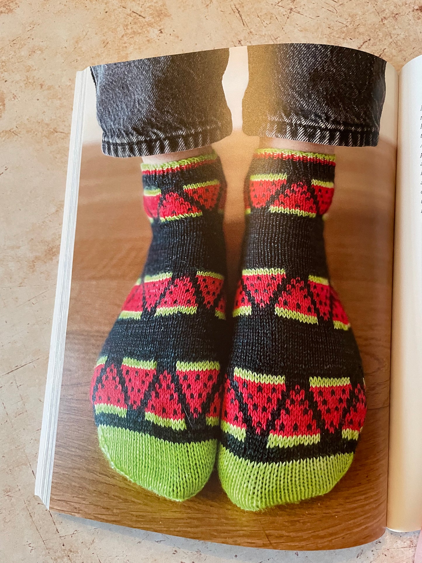 Pair of knitted socks with a watermelon pattern on a wooden surface