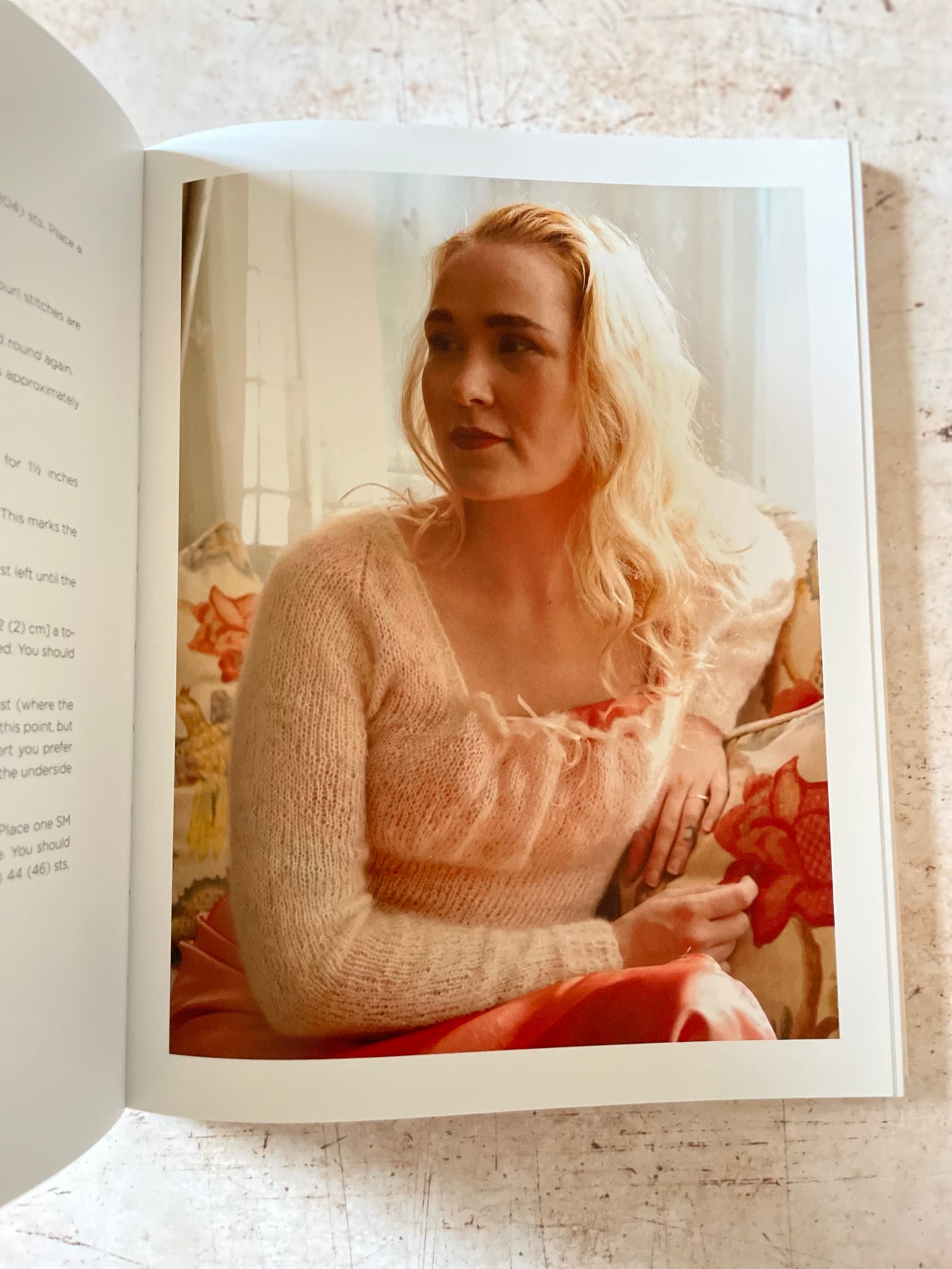 Open book with a photograph of a woman holding a red star-shaped object and wearing a cream sweater