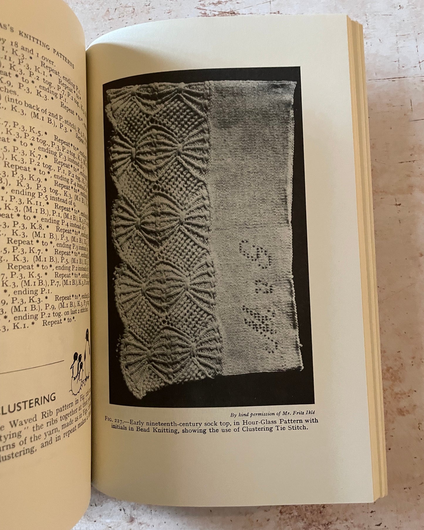 Open book with a page featuring a knitted pattern illustration on a textured surface.