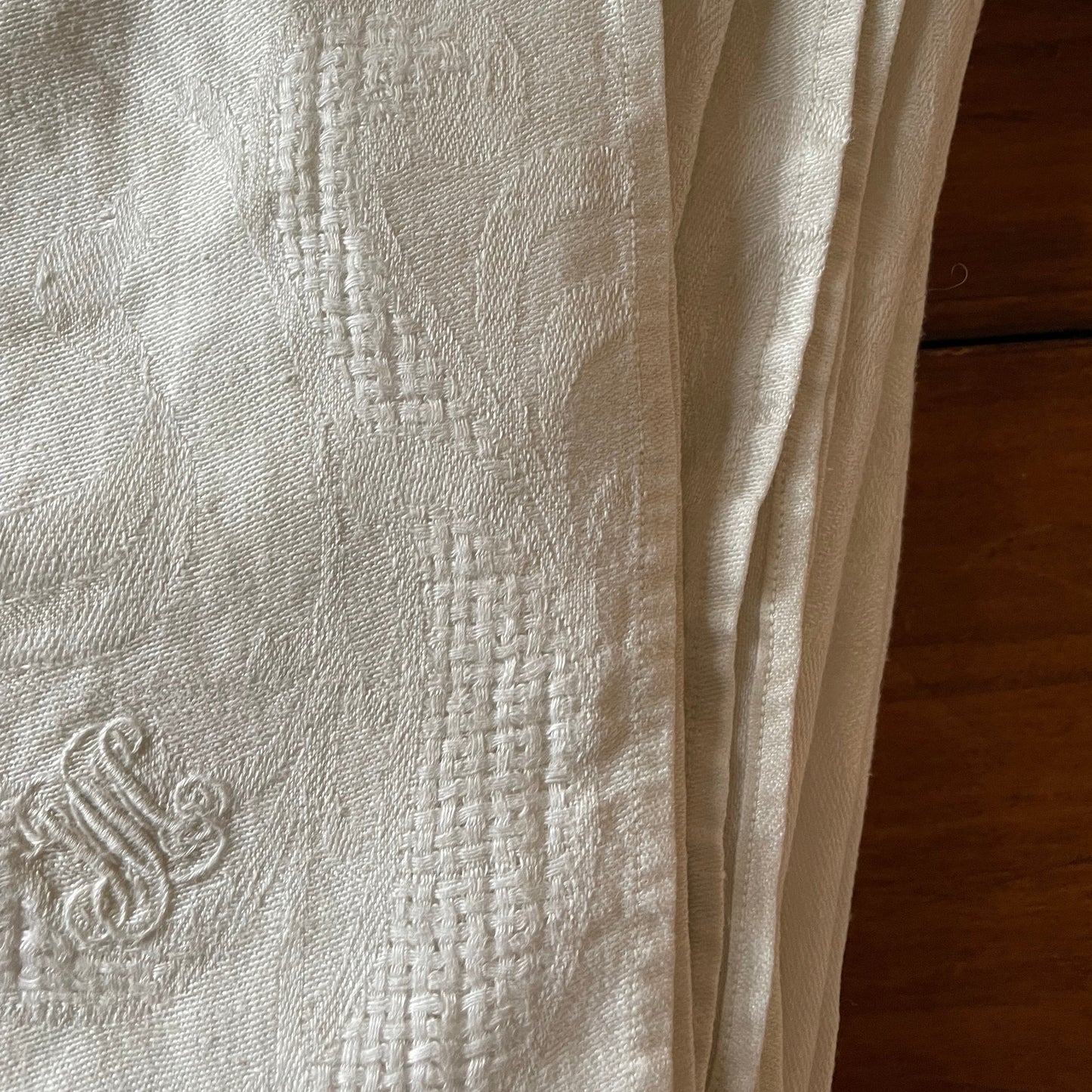 Close-up of textured linen napkin with a damask pattern and embroidered M