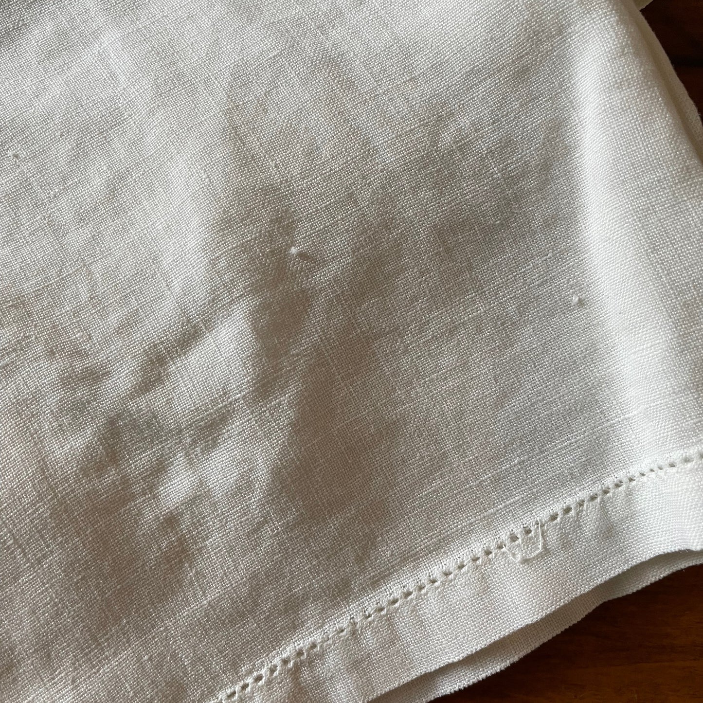 Close-up of a beige fabric with visible stitched hem on a wooden surface