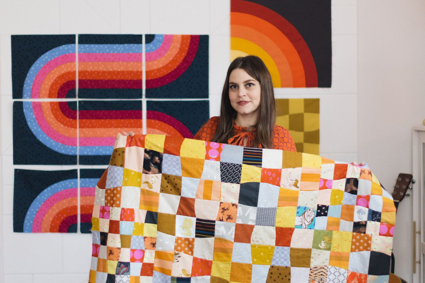 Woman holding a colorful quilt with abstract art in the background