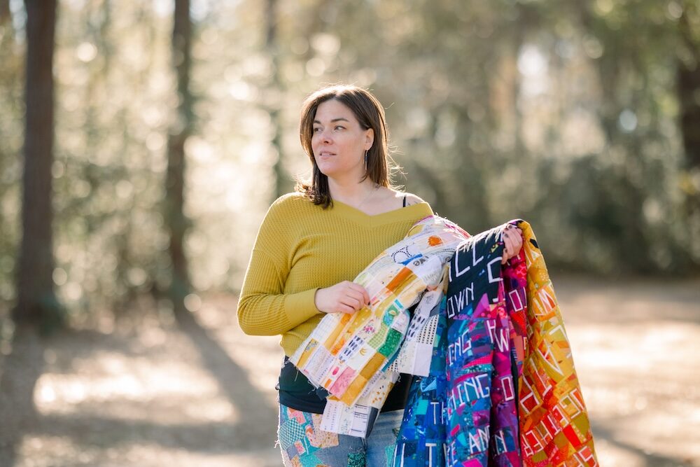 Woman holding colorful quilts in a park