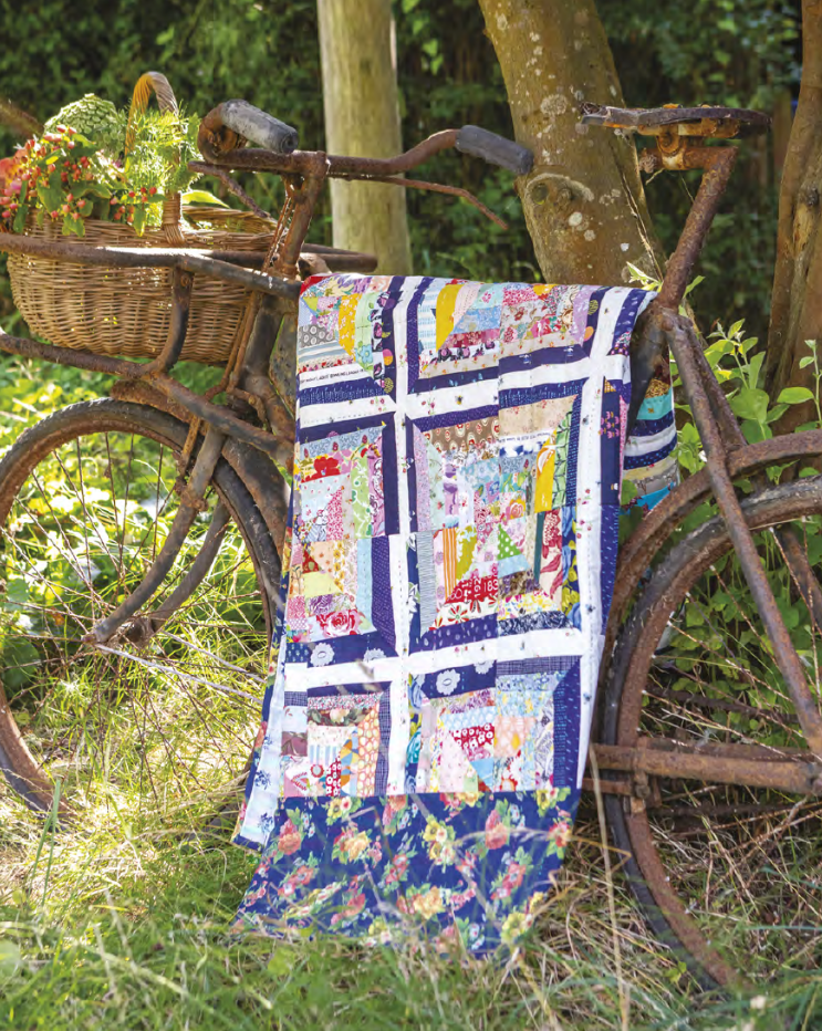 a scrappy quilt draped over a vintage bicycle