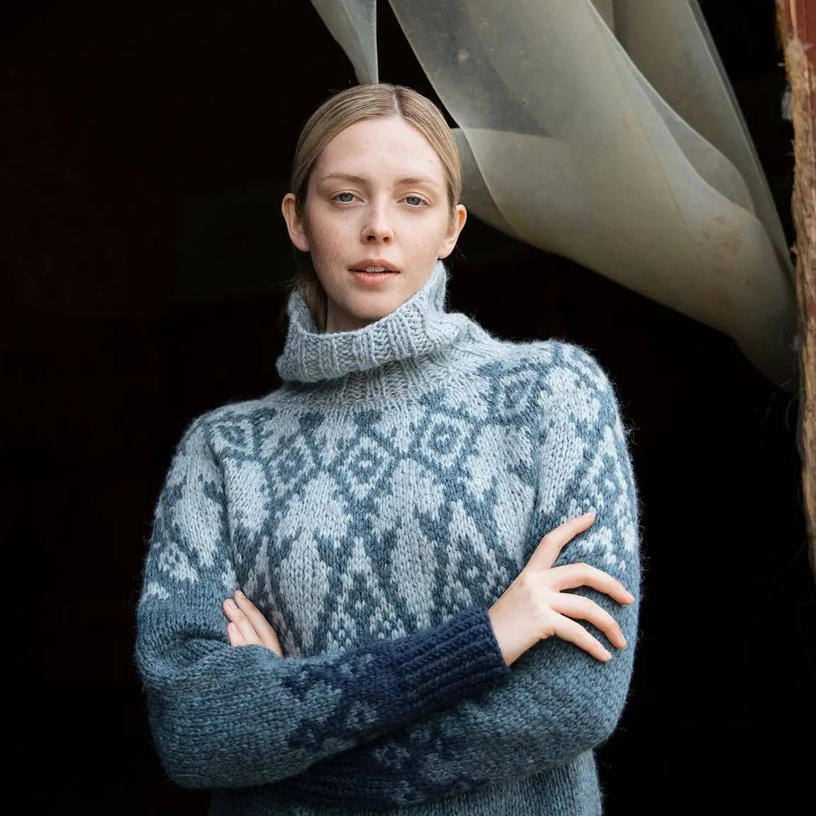 a woman wearing a blue and gray sweater