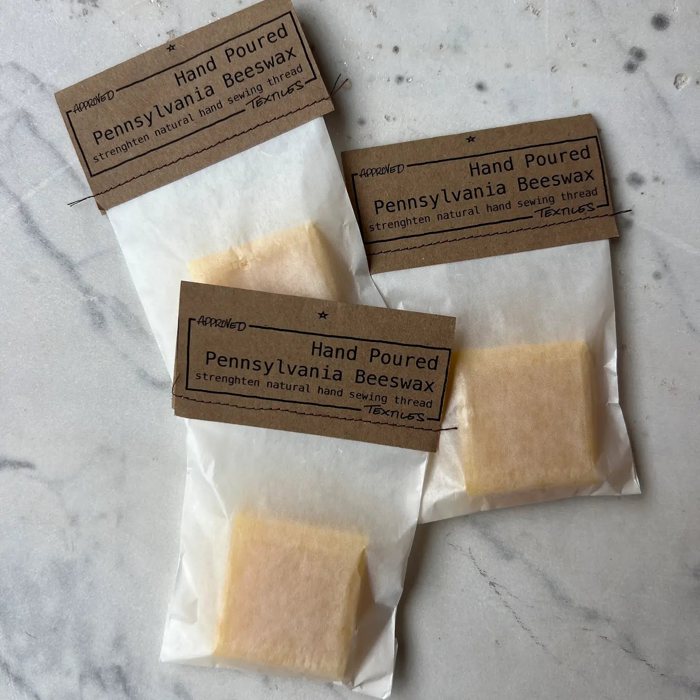 Three packages of Pennsylvania Beeswax hand poured wax on a marble surface.