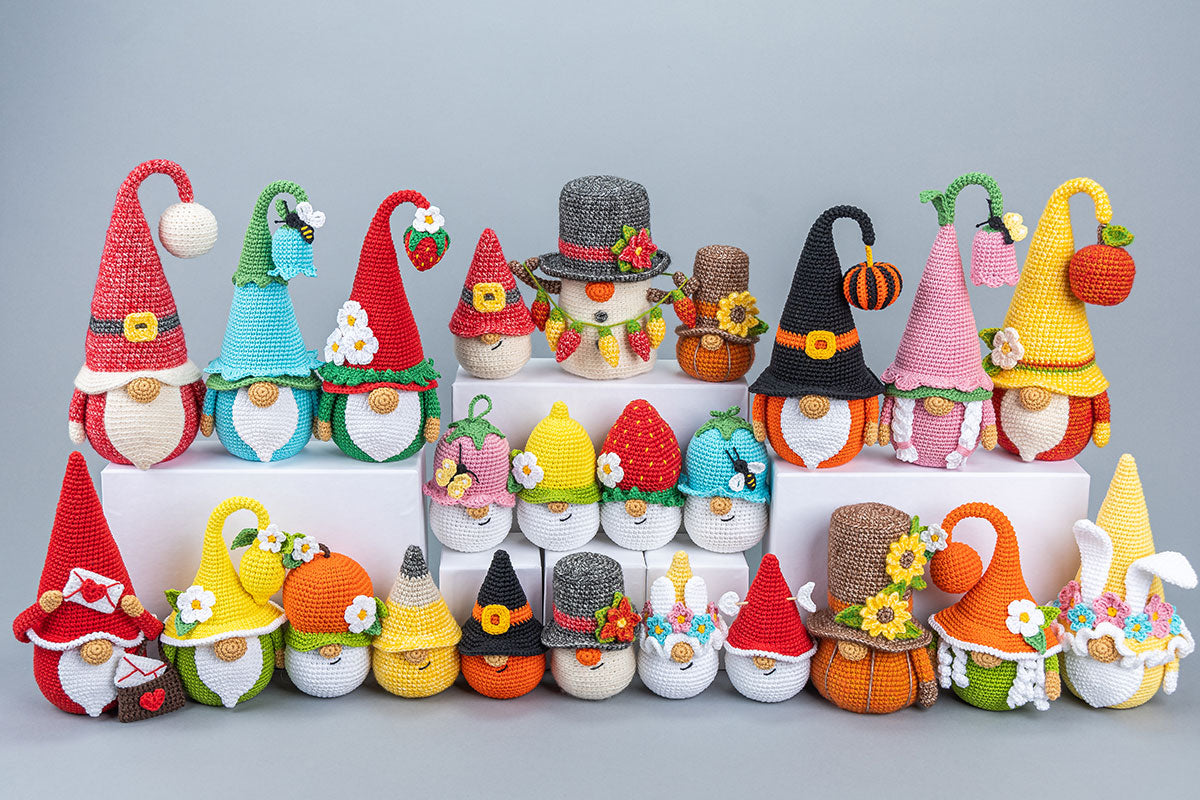 Colorful crochet gnomes with various hats and outfits on a gray background