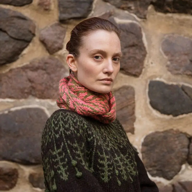 a woman wearing a black and green sweater and a pink and green scarf