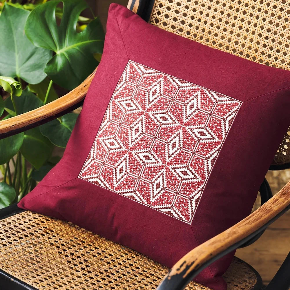 a red and white cross stitch design on a red pillow