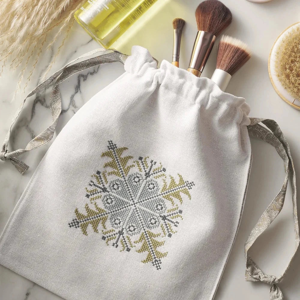 a cream drawstring bag with blue and green cross stitch embroidery