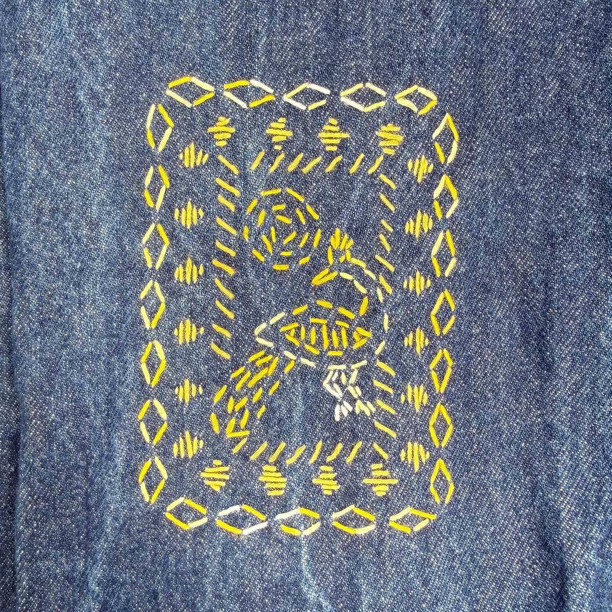 Embroidered bird on denim fabric with yellow thread