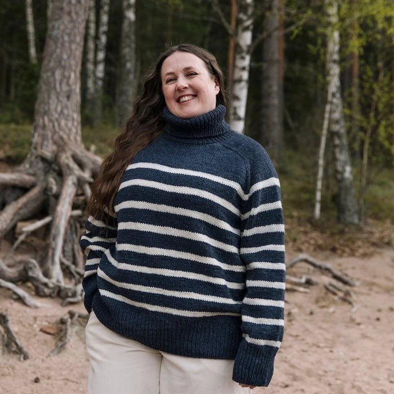 Woman wearing a striped sweater standing in a forest