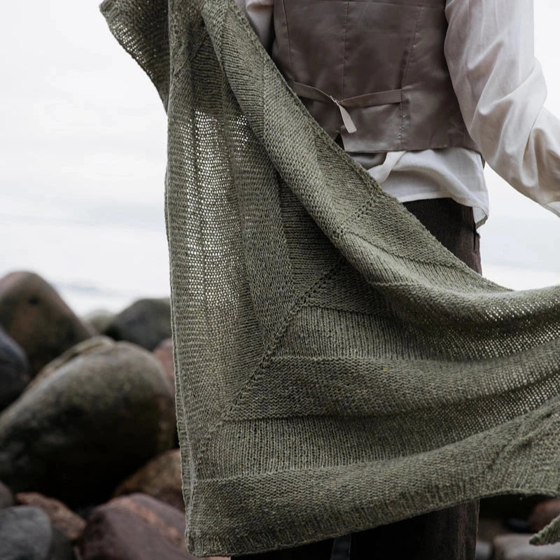 a woman standing amidst rocks with a green shawl