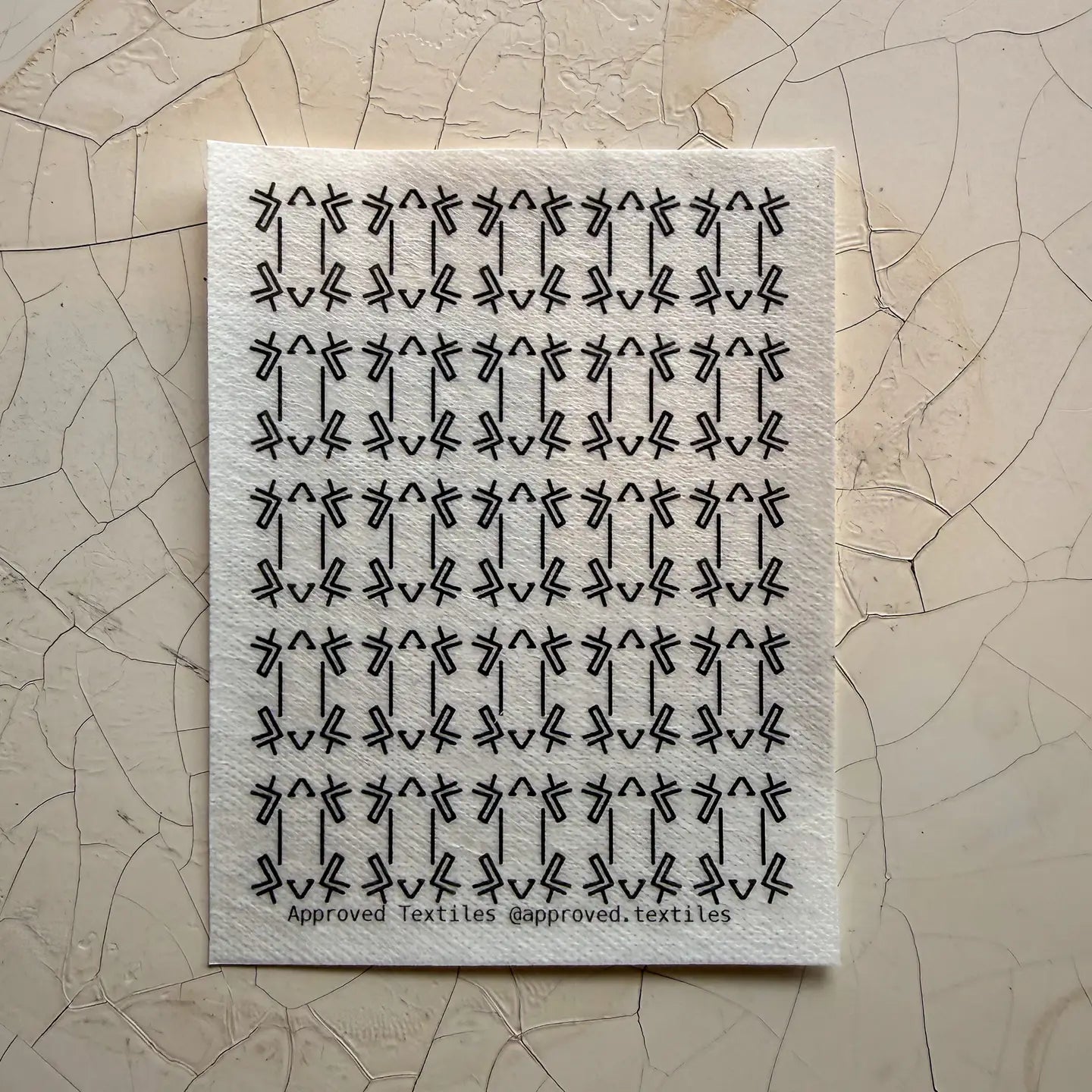 Textile sample with geometric frog feet pattern on a textured beige background