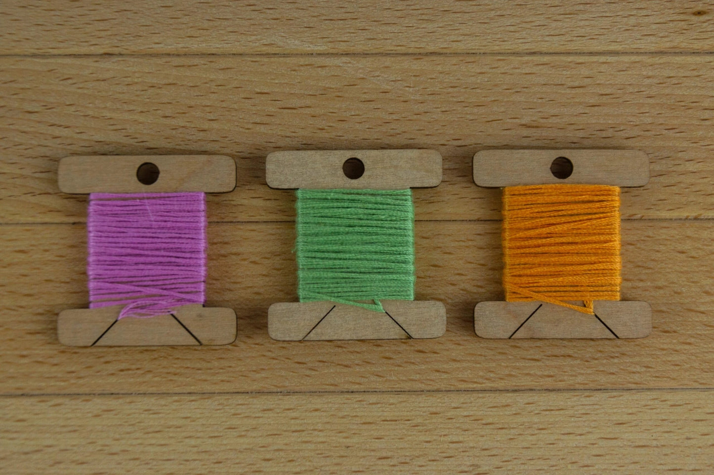 3 wooden thread bobbins with thread
