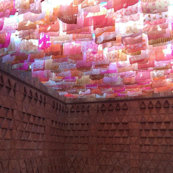 pink dyed textiles hung on the ceiling