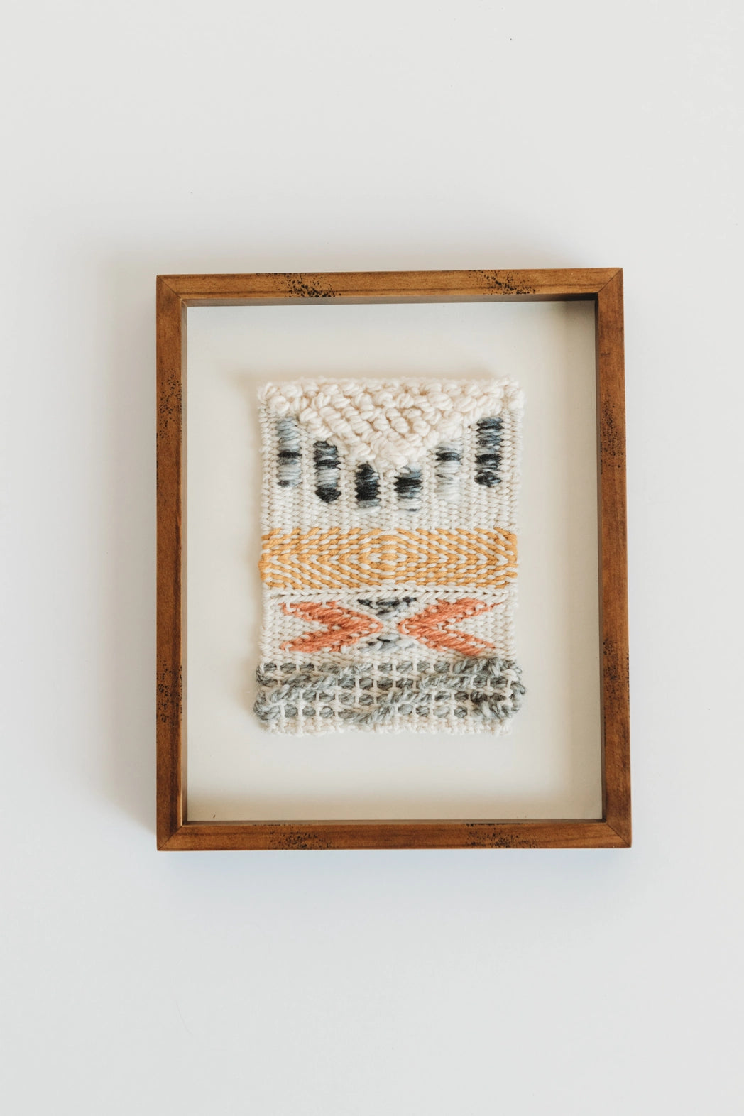 small orange and white weaving in a frame