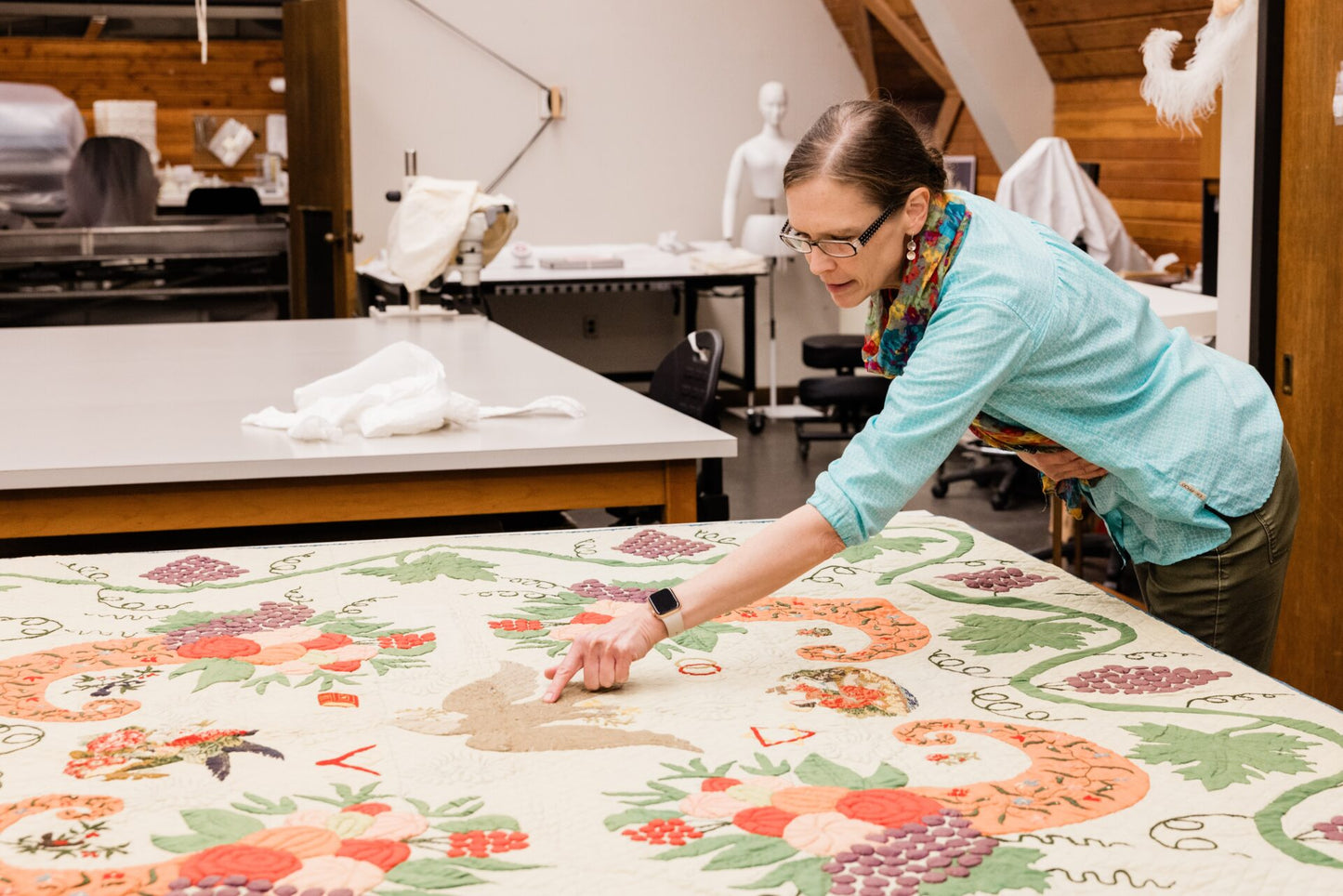 Person working on a floral quilt in a workshop setting