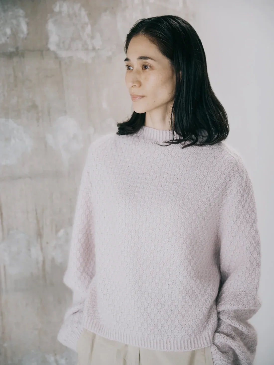 a woman wearing a neutral textured long sleeve sweater