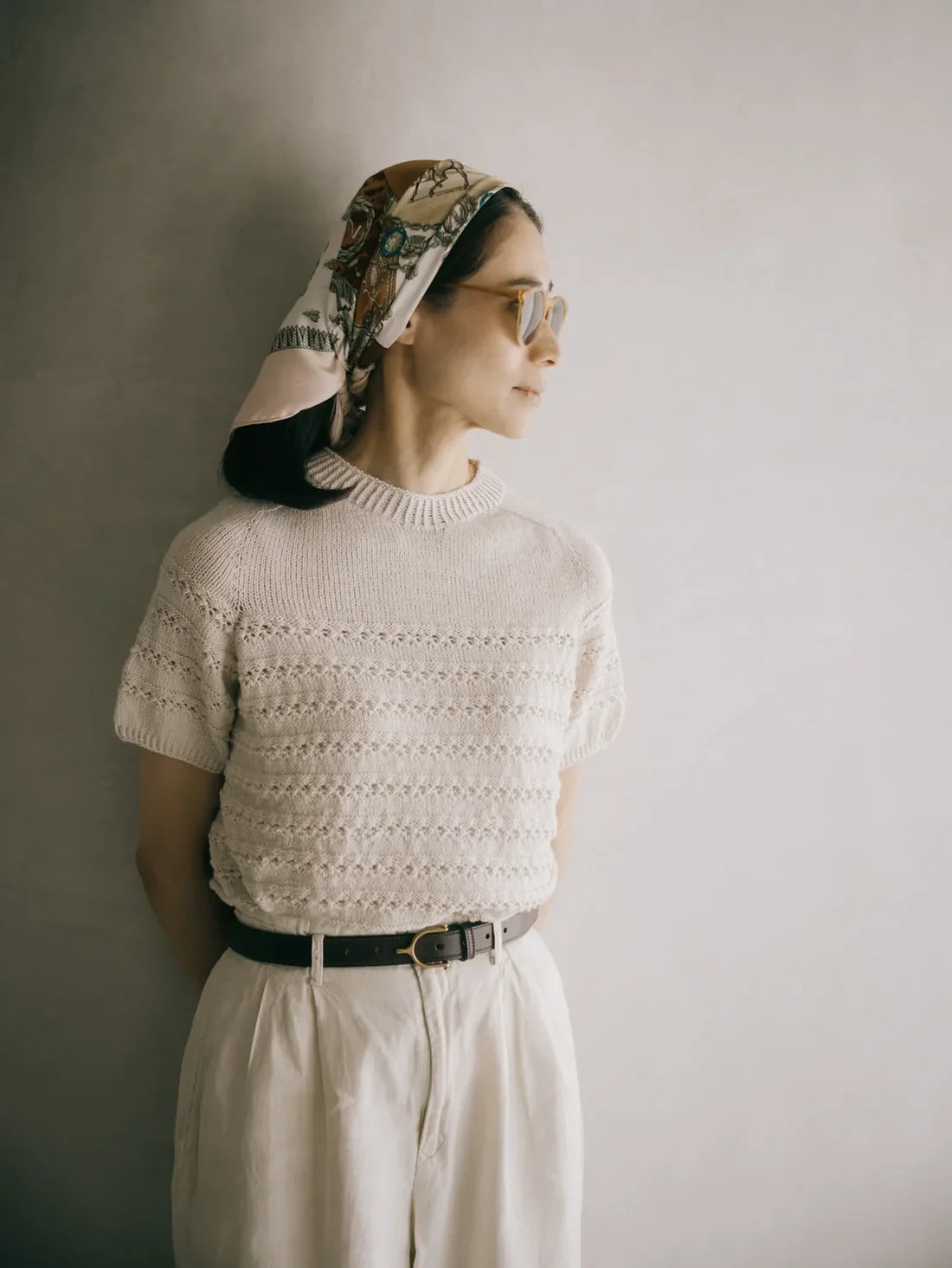 a woman wearing a textured short sleeve sweater and a head scarf