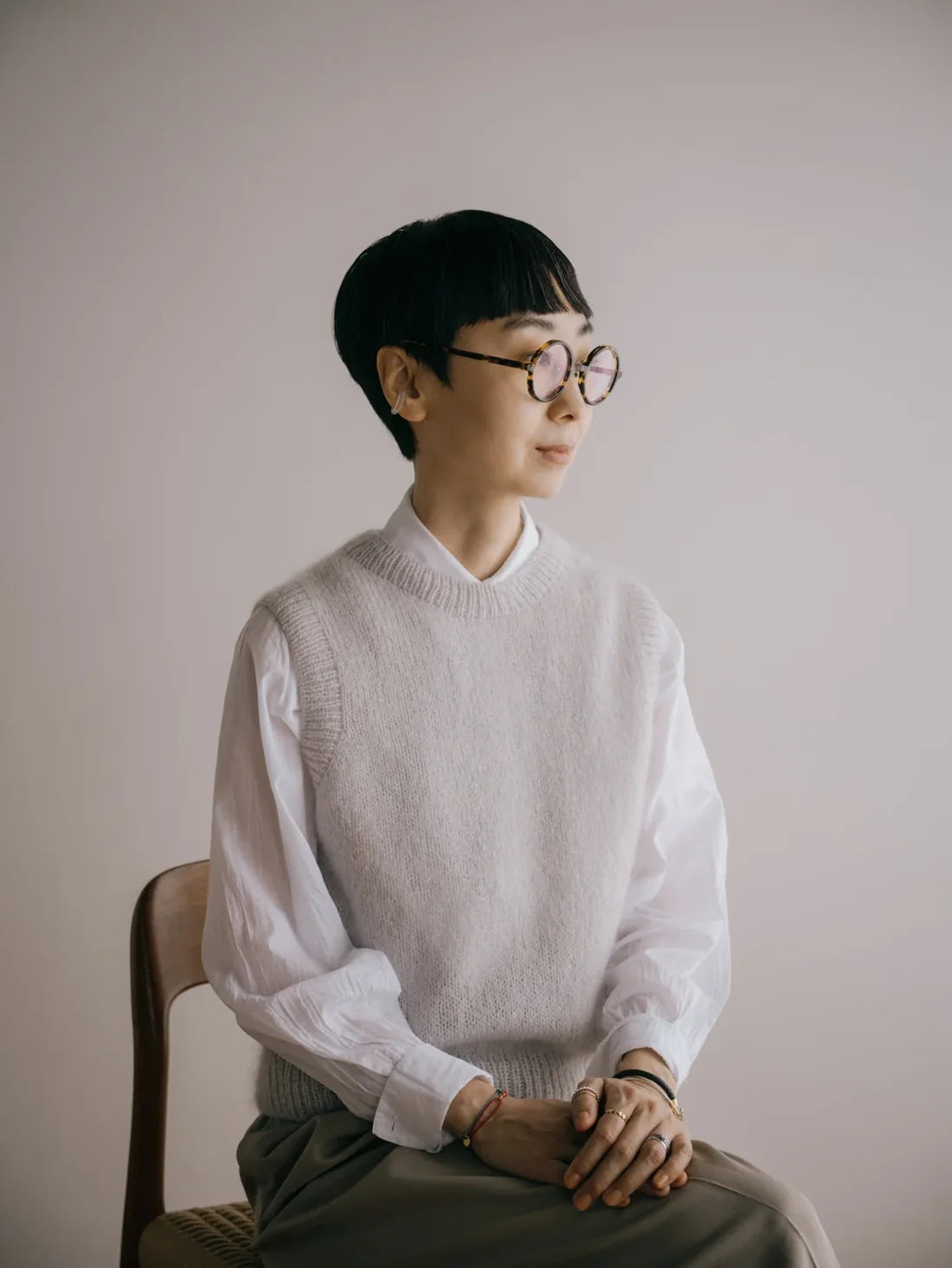 a woman with glasses wearing a light gray hand knit sweater vest