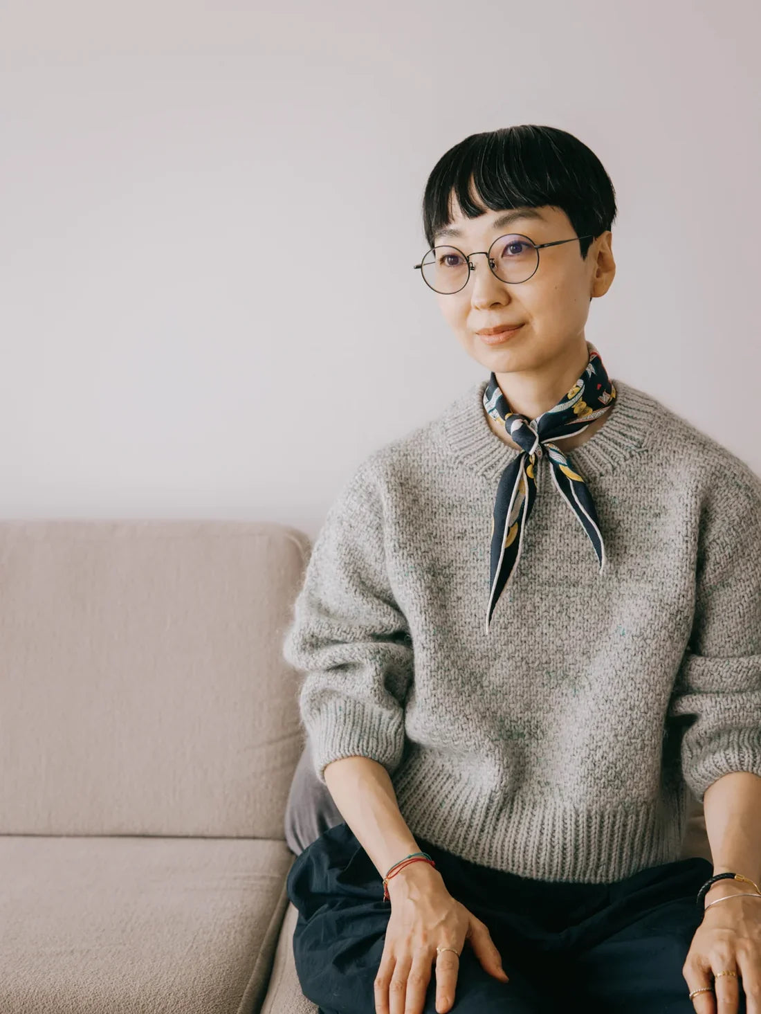 a woman wearing a gray hand knit textured sweater with a blue neck scarf