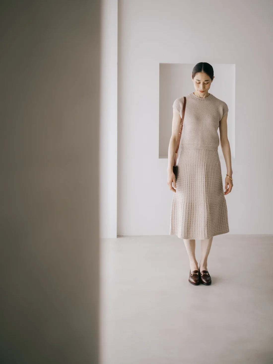a woman wearing a neutral hand knit top and skirt