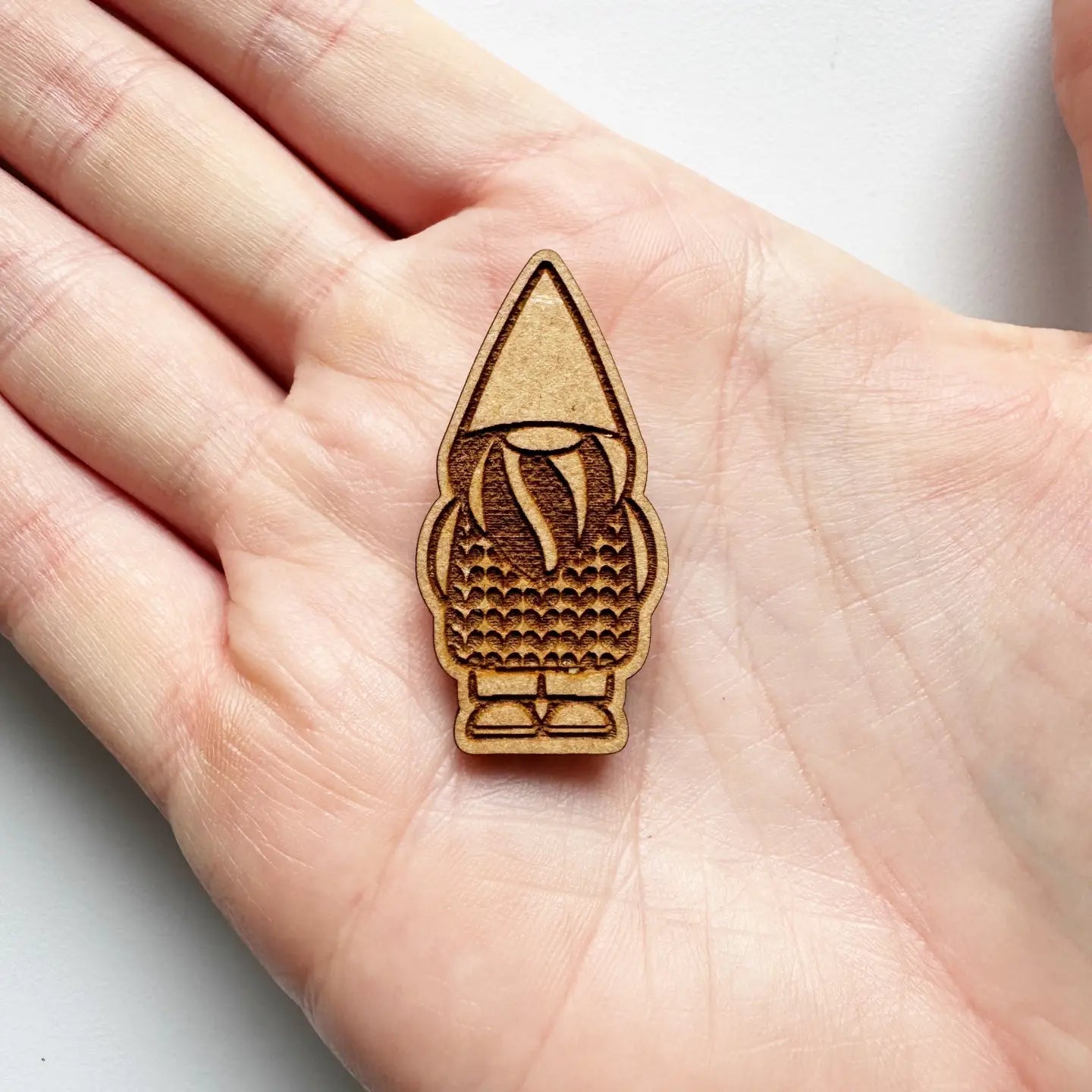 Wooden gnome needle minder  held in a hand on a white background