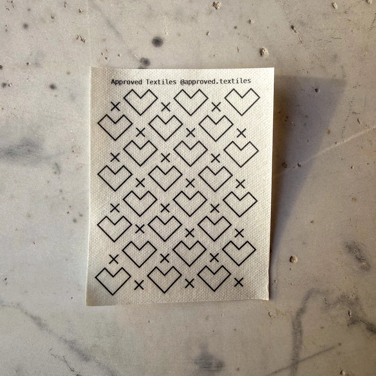 Textile sample with geometric heart pattern on a marble surface