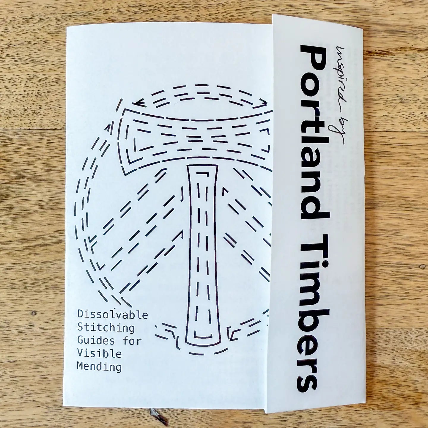 Dissolvable stitching guide for visible mending inspired by Portland Timbers on a wooden surface