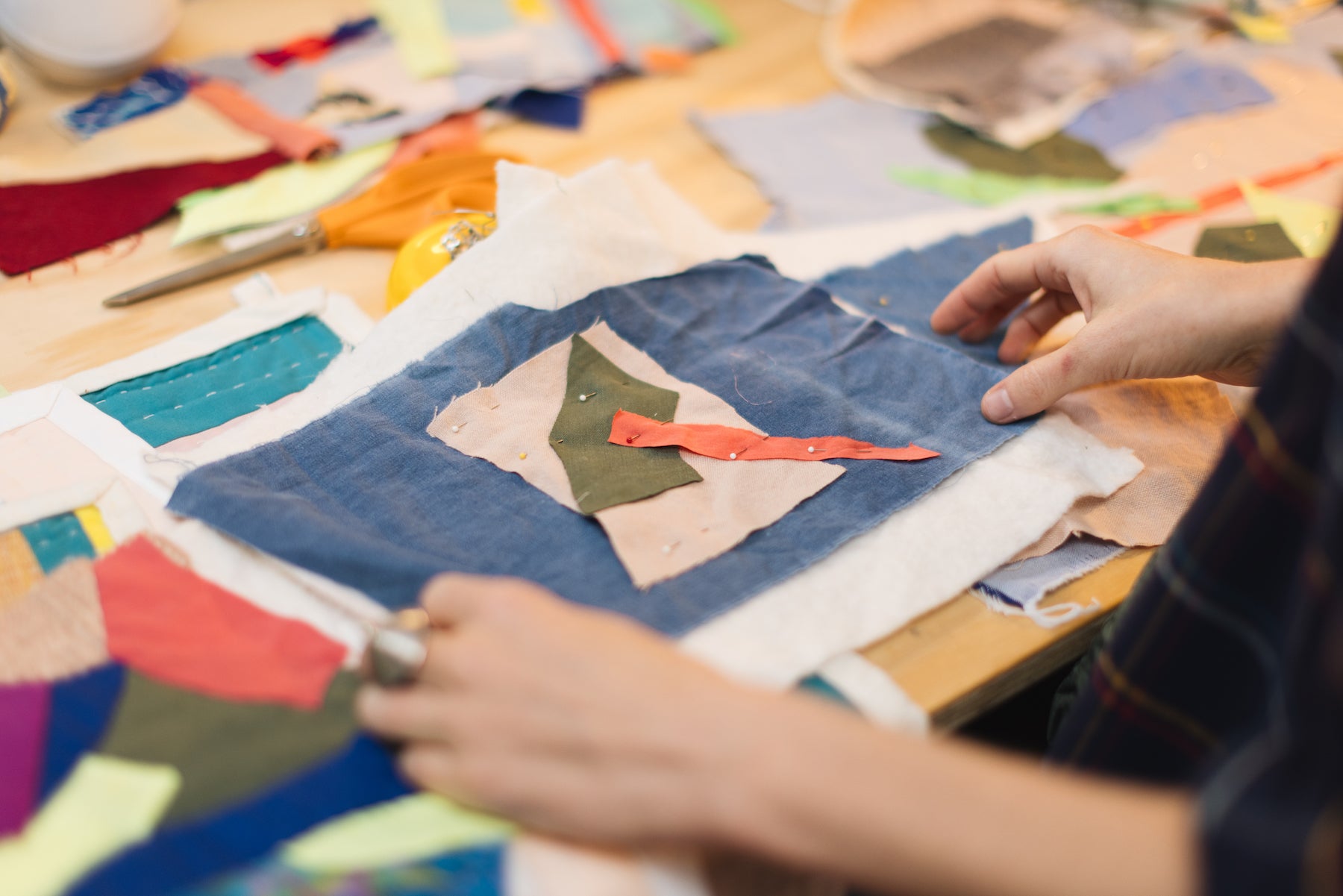 Person working with fabric pieces on a table with various tools